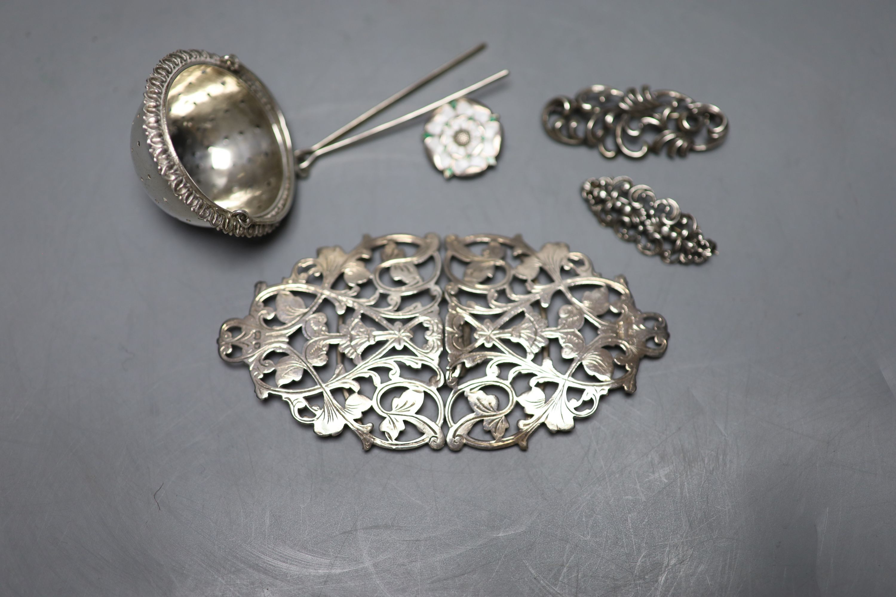 An Edwardian pierced silver belt buckle, Birmingham, 1901, 11.2cm, two brooches , rose brooch and a tea strainer.